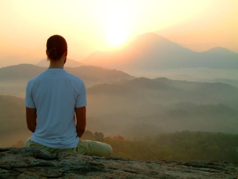 Hombre meditando ante un paisaje de montañas