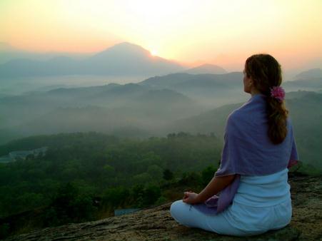 Mujer meditando ante un paisaje de montañas